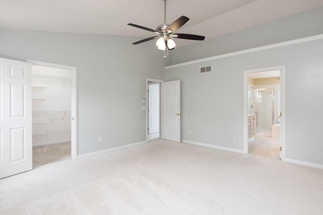 unfurnished bedroom with light colored carpet, baseboards, a spacious closet, vaulted ceiling, and a closet