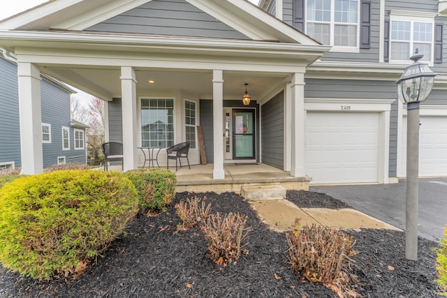 property entrance featuring a porch, an attached garage, and aphalt driveway