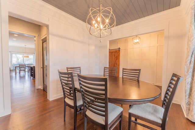 dining area with a decorative wall, dark wood-type flooring, a barn door, wood ceiling, and a notable chandelier