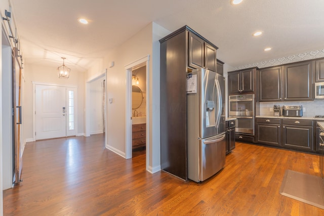 kitchen featuring dark wood finished floors, light countertops, dark brown cabinetry, and stainless steel appliances