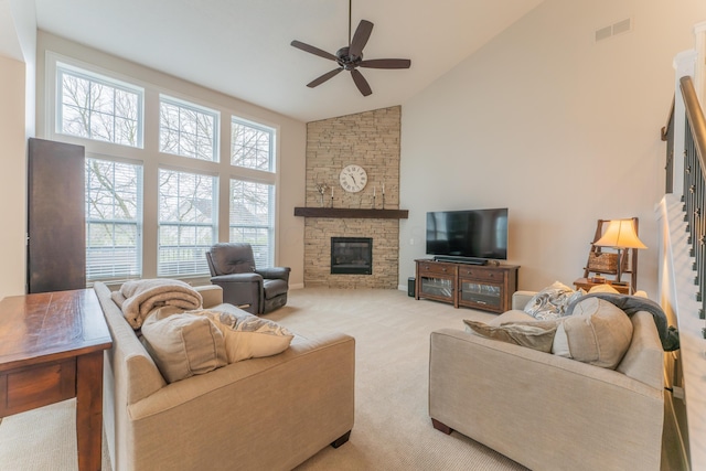 living room with high vaulted ceiling, ceiling fan, light colored carpet, visible vents, and a stone fireplace