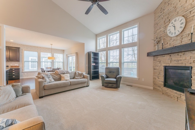living room featuring light carpet, a wealth of natural light, a fireplace, and ceiling fan