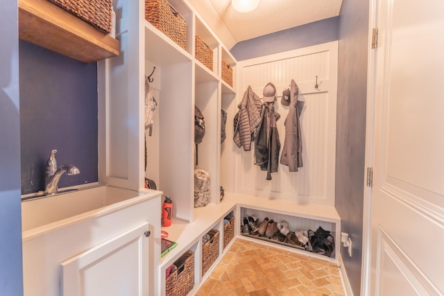 mudroom with brick floor and a sink