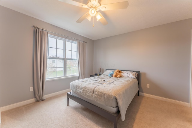bedroom with light carpet, baseboards, and a ceiling fan