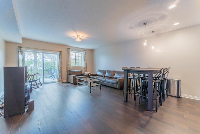 living room with a textured ceiling, wood finished floors, baseboards, and recessed lighting