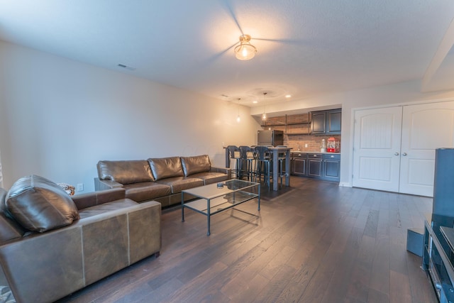 living room featuring dark wood-type flooring, visible vents, and bar