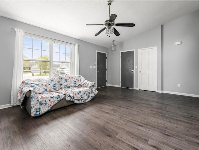 living room featuring baseboards, ceiling fan, vaulted ceiling, and dark wood finished floors