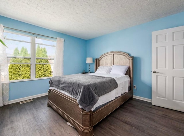 bedroom featuring visible vents, baseboards, a textured ceiling, and wood finished floors