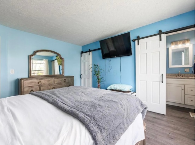 bedroom featuring a textured ceiling, a barn door, and wood finished floors