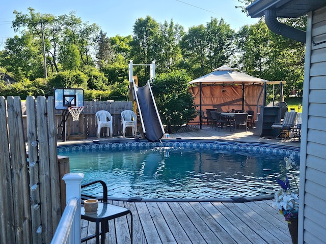 view of swimming pool with outdoor dining area, fence, a wooden deck, and a gazebo