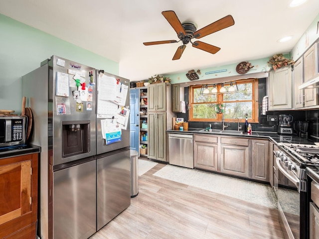 kitchen featuring light wood-style flooring, ceiling fan, a sink, dark countertops, and stainless steel appliances