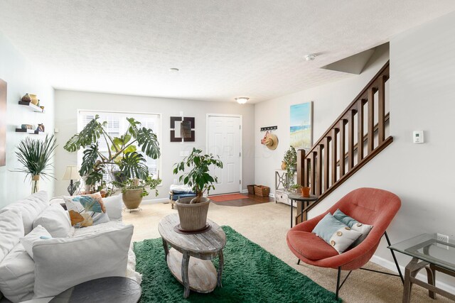 living room with carpet, stairway, and a textured ceiling
