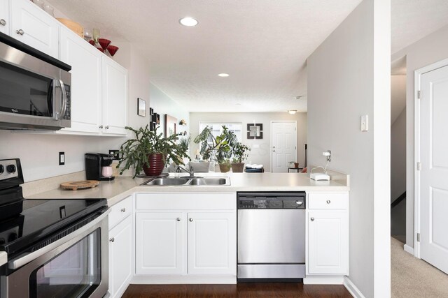 kitchen with white cabinetry, stainless steel appliances, light countertops, and a sink
