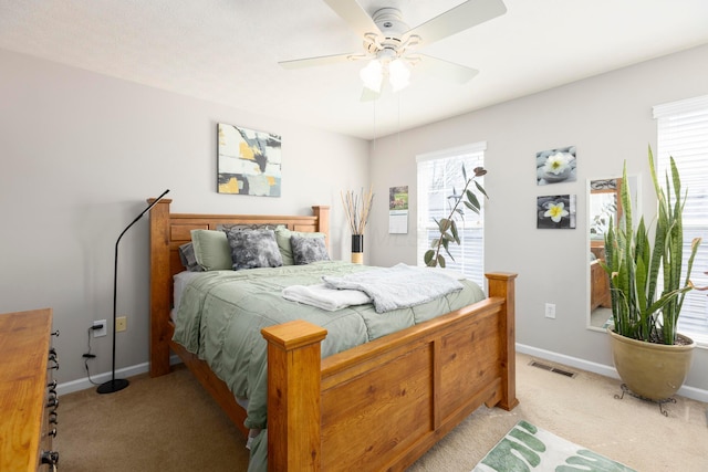 bedroom featuring a ceiling fan, visible vents, light carpet, and baseboards