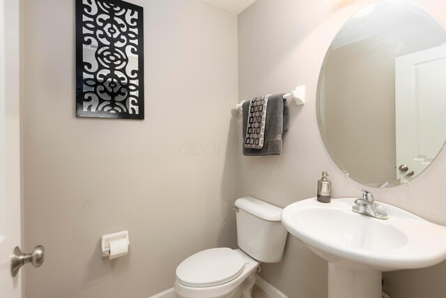 half bathroom featuring a sink, toilet, and baseboards