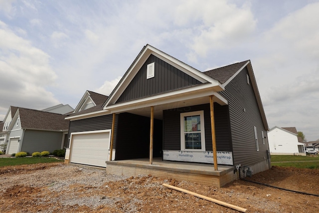 view of front of home with board and batten siding, gravel driveway, a porch, and a garage