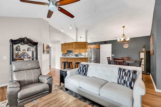 living room with lofted ceiling, light wood-style floors, and ceiling fan with notable chandelier