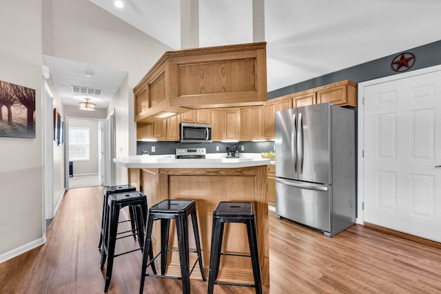 kitchen featuring light wood-style flooring, visible vents, a breakfast bar, appliances with stainless steel finishes, and light countertops