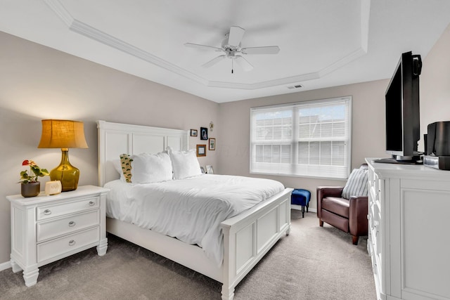 bedroom featuring crown molding, a tray ceiling, baseboards, and light carpet