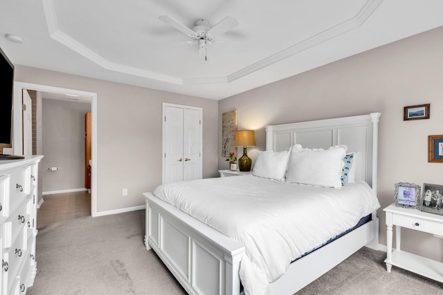 bedroom featuring light colored carpet, a tray ceiling, baseboards, and crown molding
