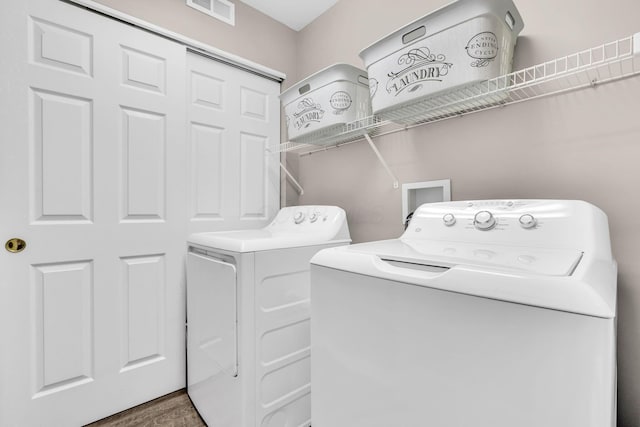 laundry area featuring visible vents, washing machine and clothes dryer, wood finished floors, and laundry area