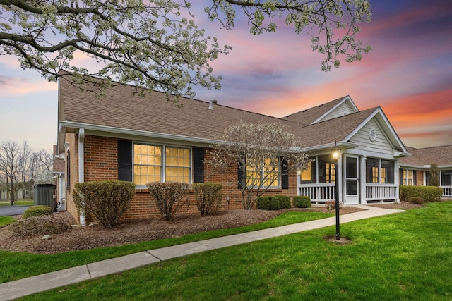 view of front of property with central air condition unit, roof with shingles, a front yard, and brick siding