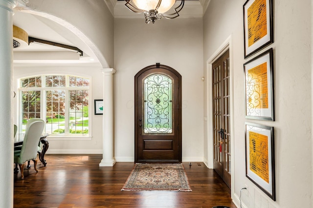 10577 Wellington Blvd, Powell, OH 43065 - entrance foyer with decorative columns, dark wood finished floors, baseboards, arched walkways, and a chandelier