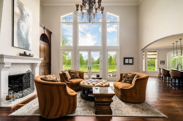 10577 Wellington Blvd, Powell, OH 43065 - living room with a chandelier, arched walkways, ornamental molding, wood finished floors, and a towering ceiling