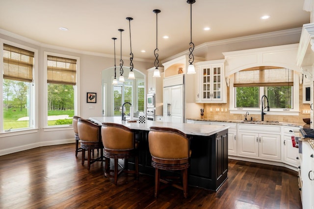 10577 Wellington Blvd, Powell, OH 43065 - kitchen with a sink, healthy amount of natural light, built in appliances, white cabinetry, and ornamental molding