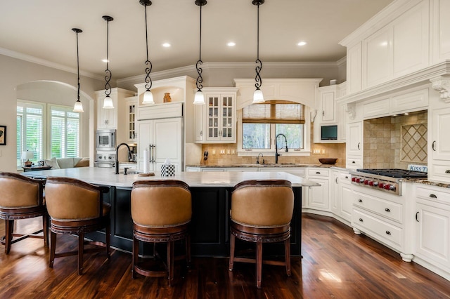 10577 Wellington Blvd, Powell, OH 43065 - kitchen with a sink, built in appliances, a kitchen island with sink, plenty of natural light, and ornamental molding