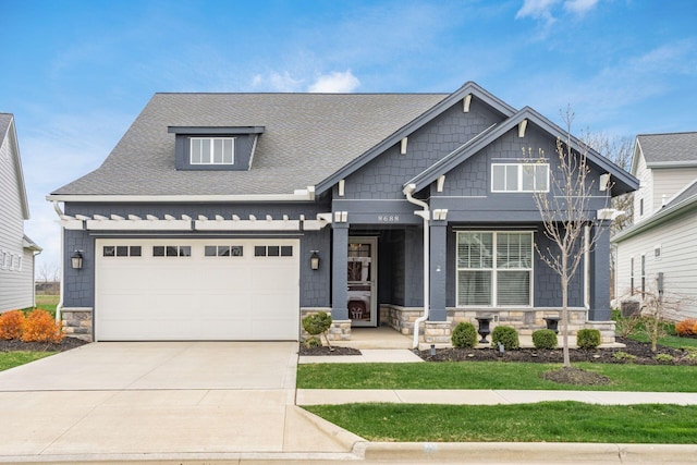8688 Eliot Dr, Plain City, OH 43064 - craftsman-style house with an attached garage, a shingled roof, concrete driveway, and stone siding