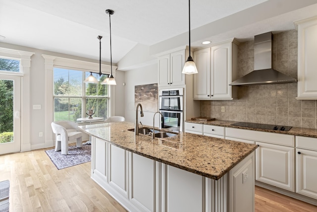 3697 Echo Pl, Powell, OH 43065 - kitchen with black electric cooktop, wall chimney exhaust hood, light wood-style flooring, vaulted ceiling, and double oven