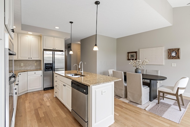 3697 Echo Pl, Powell, OH 43065 - kitchen featuring a sink, decorative backsplash, stainless steel appliances, a center island with sink, and light wood-style flooring