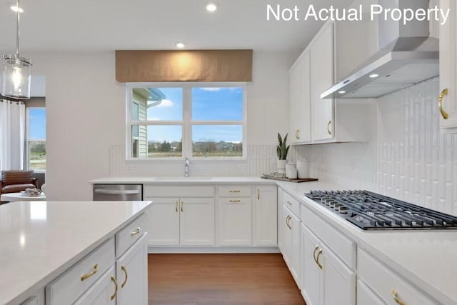 kitchen featuring wall chimney range hood, appliances with stainless steel finishes, a sink, and plenty of natural light
