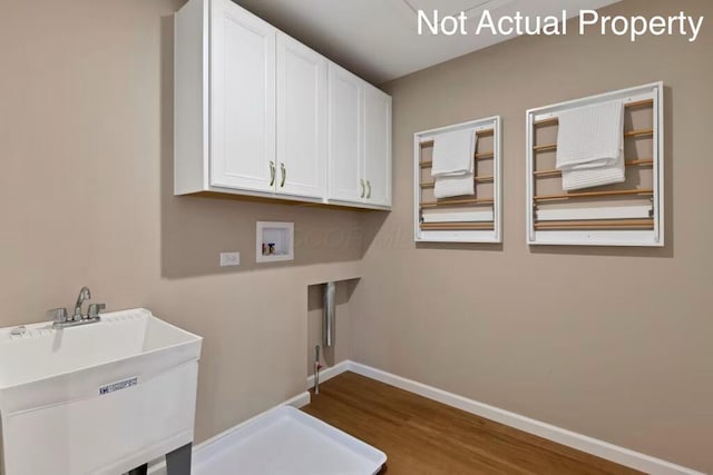 laundry room with wood finished floors, a sink, baseboards, cabinet space, and washer hookup