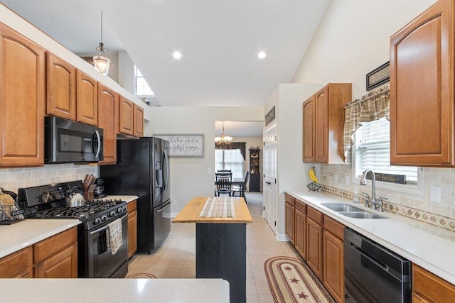 kitchen featuring tasteful backsplash, black appliances, light countertops, a sink, and a notable chandelier