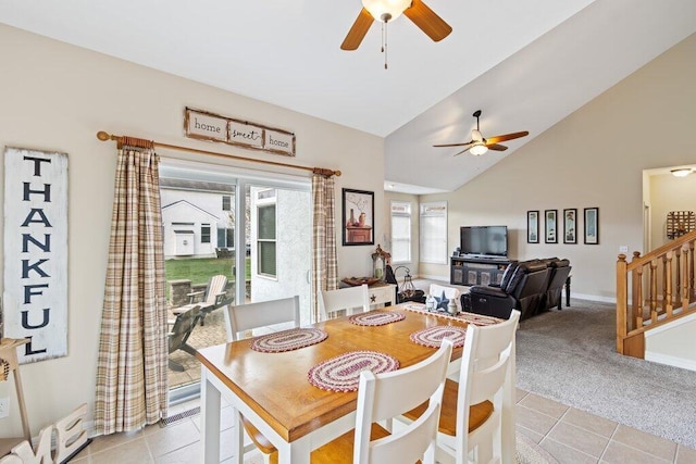 dining space with light tile patterned floors, baseboards, ceiling fan, high vaulted ceiling, and light colored carpet