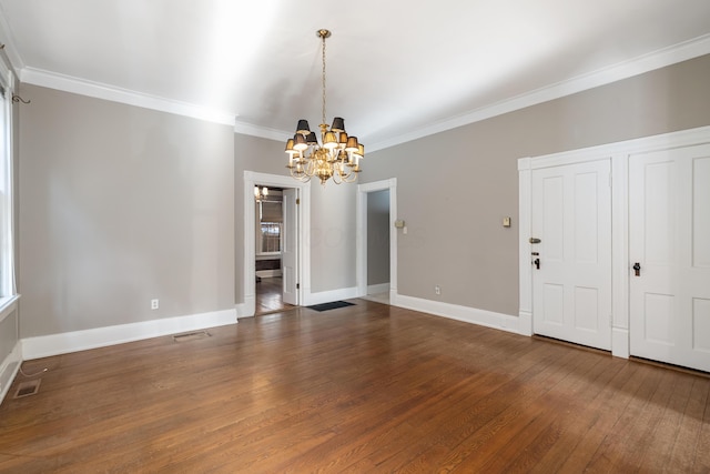 unfurnished dining area with a chandelier, ornamental molding, wood finished floors, and baseboards
