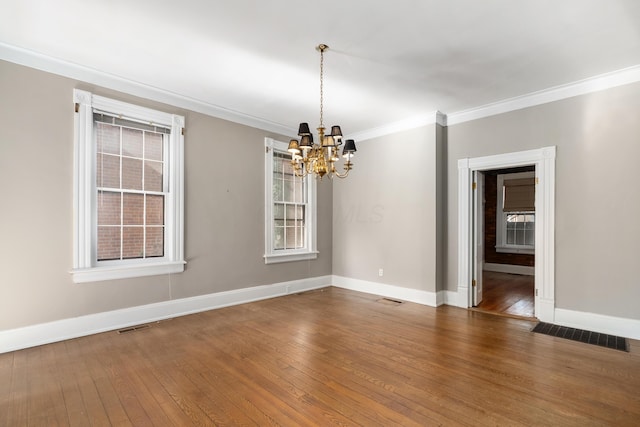 spare room with a chandelier, crown molding, wood-type flooring, and baseboards