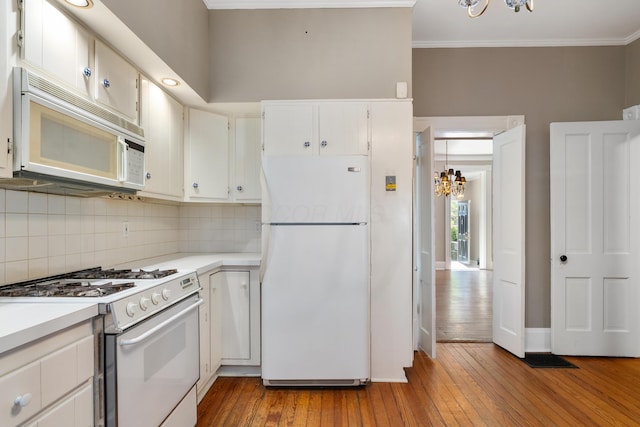 kitchen featuring white appliances, a chandelier, crown molding, tasteful backsplash, and hardwood / wood-style floors