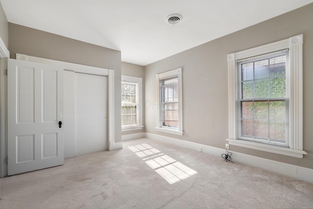 unfurnished bedroom featuring carpet floors, multiple windows, and a closet