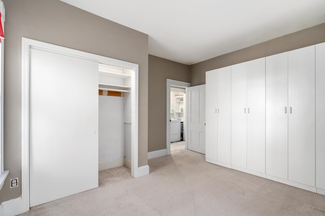 unfurnished bedroom with light carpet, washer / clothes dryer, and baseboards