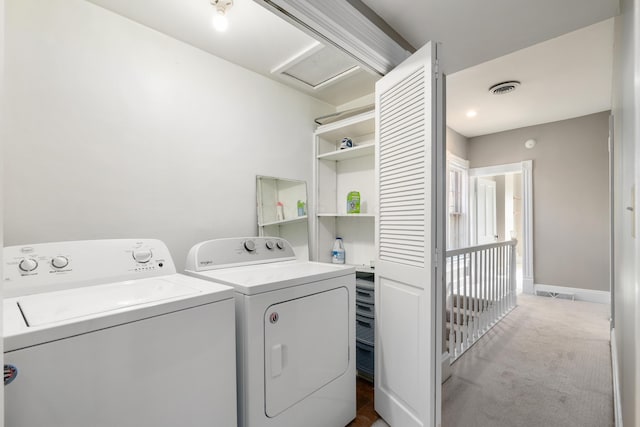 washroom featuring washing machine and clothes dryer, light carpet, and attic access