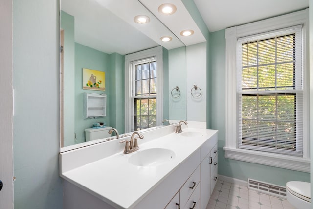 full bath featuring toilet, baseboards, recessed lighting, and double vanity
