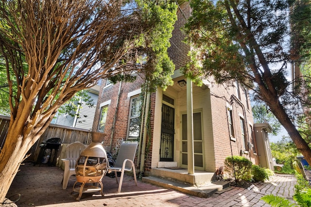 view of side of property featuring brick siding and fence