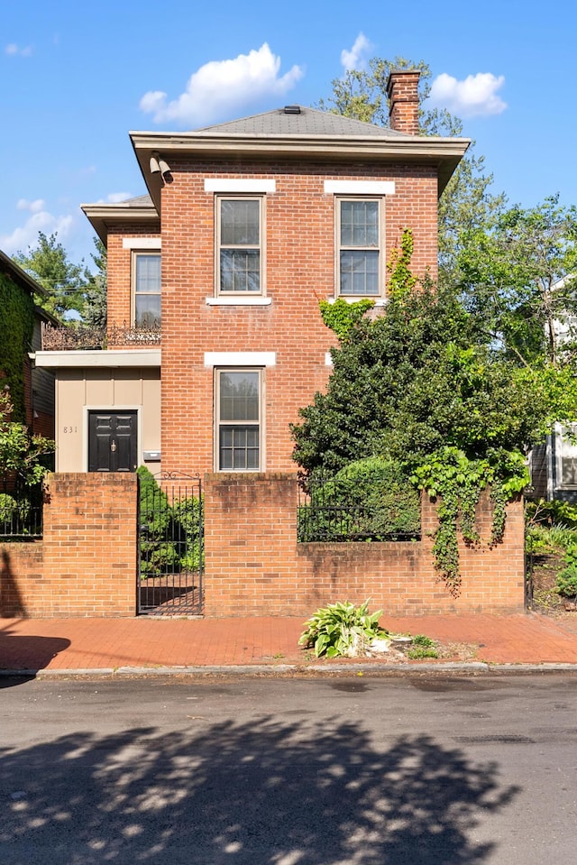 view of front of house with a fenced front yard, a chimney, and brick siding