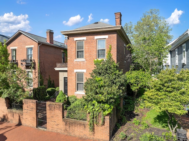 view of front facade featuring a fenced front yard, brick siding, a gate, and a chimney