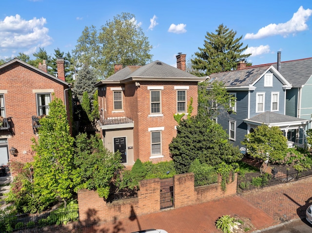 view of front of home with fence, brick siding, and a chimney