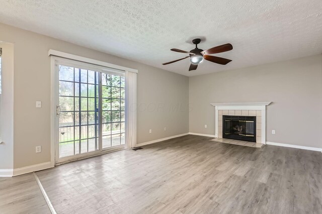 3225 Bellerive Dr, Pickerington, OH 43147 - unfurnished living room featuring visible vents, a tiled fireplace, a ceiling fan, a textured ceiling, and wood finished floors
