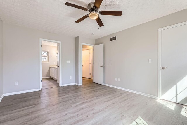 3225 Bellerive Dr, Pickerington, OH 43147 - unfurnished bedroom featuring visible vents, baseboards, a textured ceiling, connected bathroom, and wood finished floors